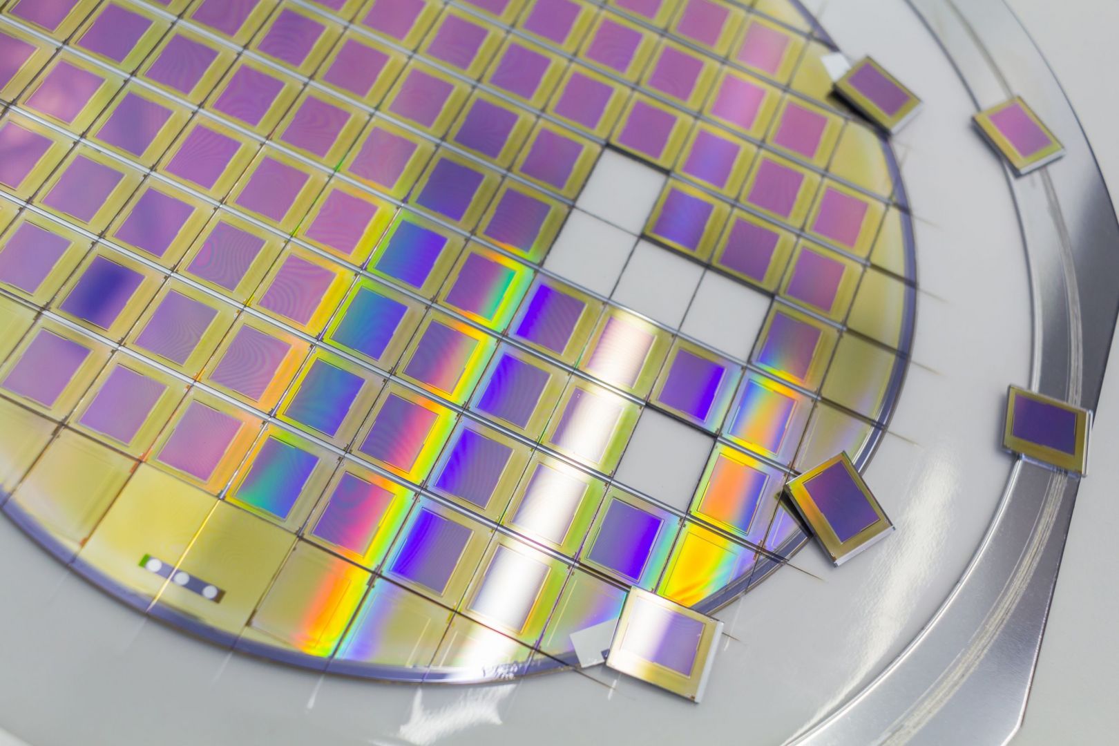 Silicon wafer with microchips fixed in a holder with a steel frame after the dicing process and separate microchips.